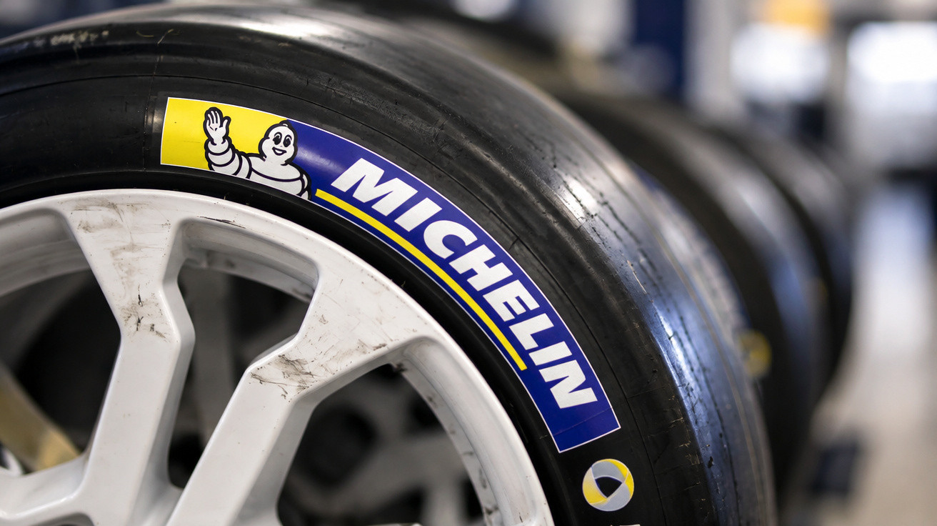 Pneus Michelin pretos montados em jantes brancas, foco no logo da marca numa oficina ou garagem.